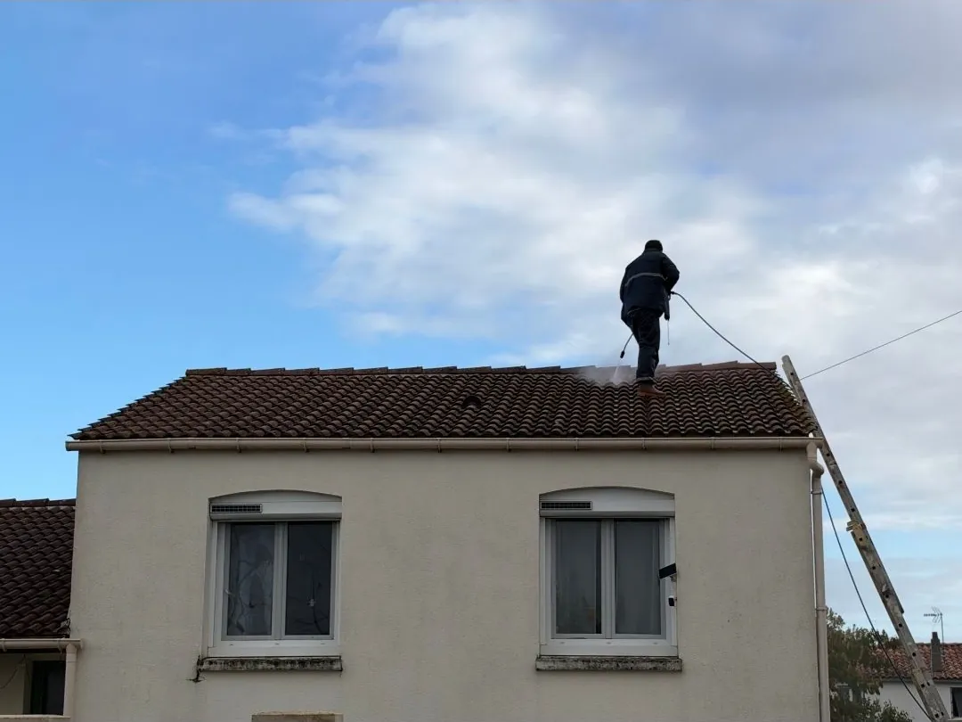 Jojakim Klein sur un toit de tuiles, en train de le nettoyer